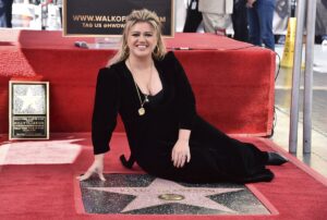 Kelly Clarkson poses on the sidewalk next to her new star on the Hollywood Walk of Fame.
