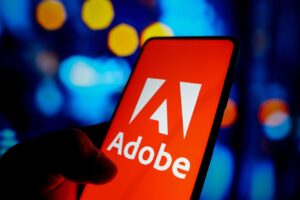 In this photo illustration, the Adobe Inc. logo seen...