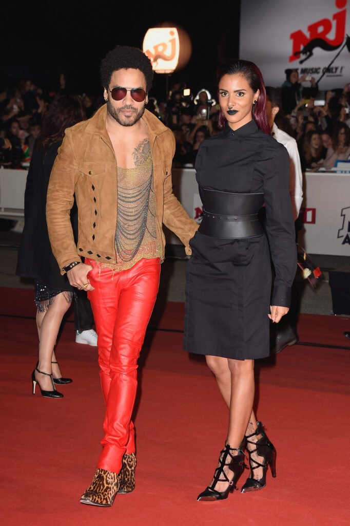 Lenny Kravitz (L) in red leather pants and tan jacket walking next to Shy