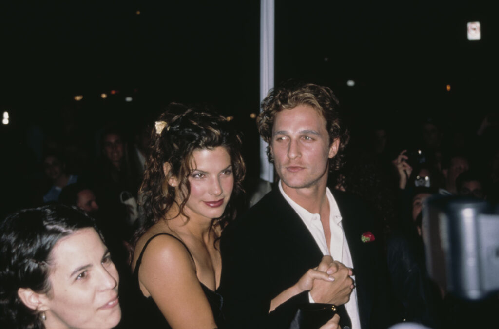 Sandra Bullock (L) in black dress sitting next to Matthew McConaughey, who is wearing a black  blazer over a white dress shirt