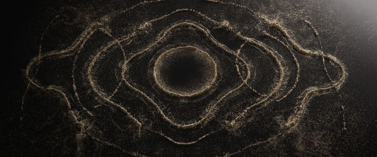 A wide shot of concentric, rippling circles formed out of sand and dust.