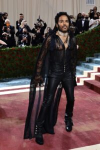 Lenny Kravitz on red carpet wearing all black outfit with cape