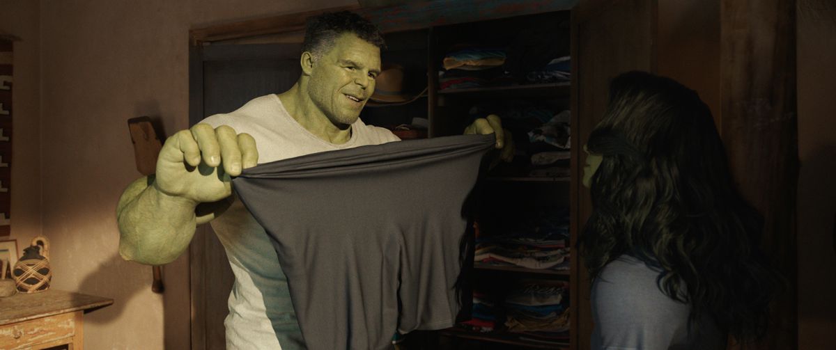 Bruce Banner as Smart Hulk holding up spandex shorts and stretching them in front of Jen, who’s in She-Hulk persona