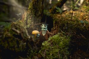A Lego version of Frankenstein’s Monster stands in the woods as a beam of light illuminates a mushroom in his hand