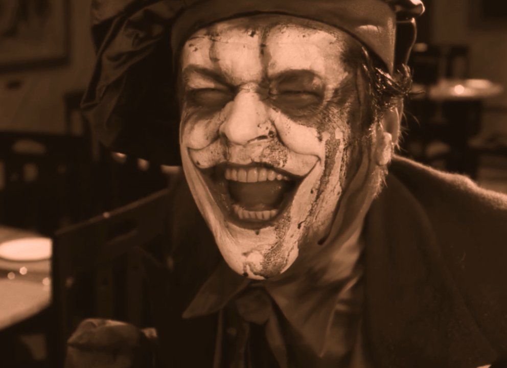 Jack Nicholson as the Joker howling with laughter as his makeup peels off to reveal his bleach white skin in Batman: The Silent Motion Picture.