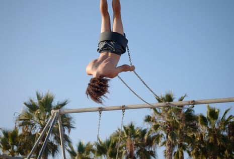Topsy Turvy – a young man swings above the palms, Santa Monica beach