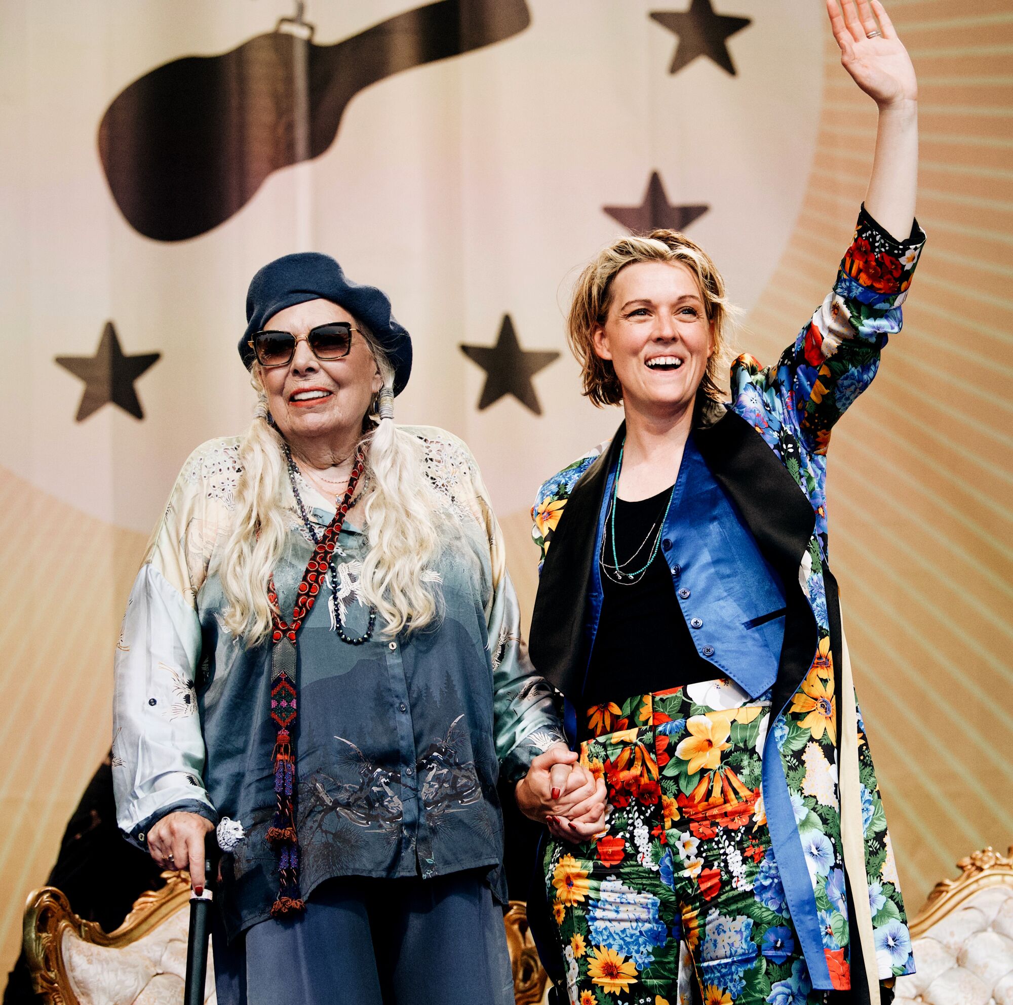 Two female singer-songwriters on stage together, waving at the crowd