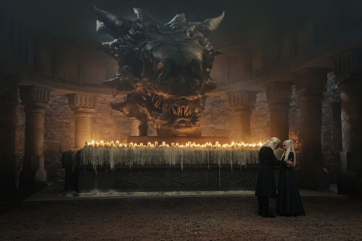 Viserys talking to his daughter in front of an altar with a bunch of candles and a giant dragon skull in House of the Dragon