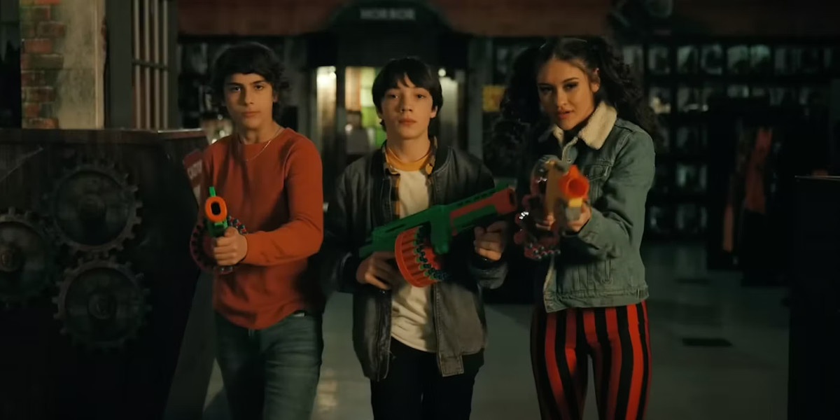 Three teenagers with playguns walk towards the camera in Spirit Halloween.