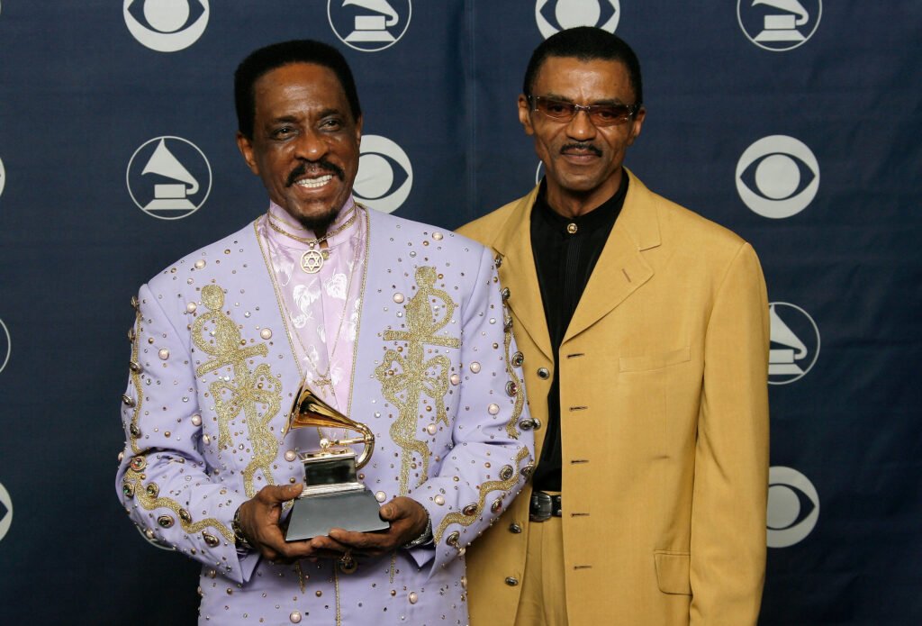 Ike Turner (L) and Ike Turner Jr. (R) pose with a Grammy award against a black backdrop