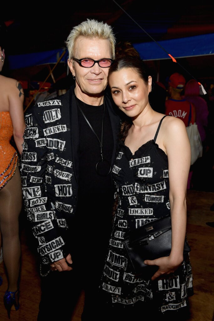 Billy Idol (L) and China Chow wearing matching black outfits with white rectangles
