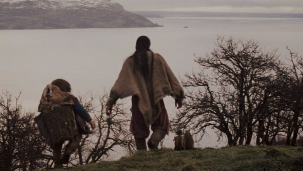 Willow, Elora Dannan, Madmartigan, and the Brownies walk over a rise above a lake in the movie Willow