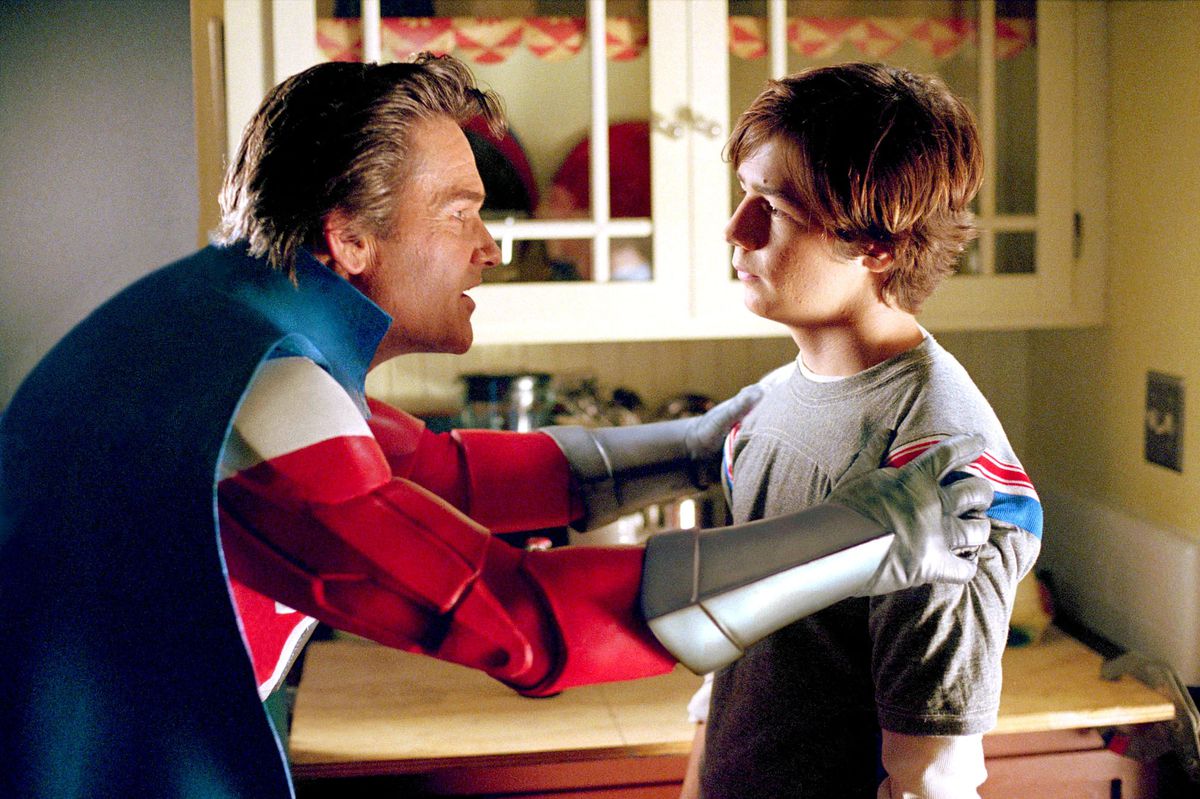 kurt russell in his superhero costume holds a young michael angarano by the shoulders in sky high