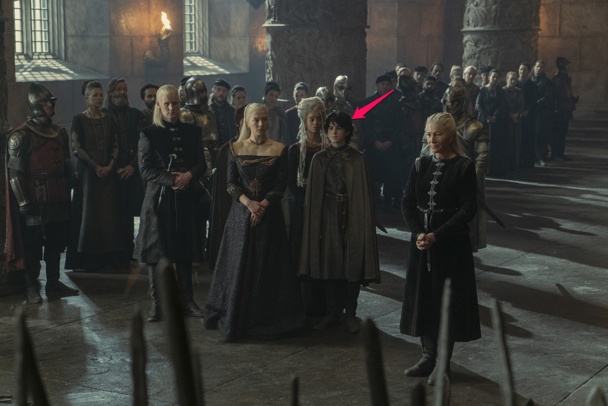Lucerys Velaryon standing with his family including Rhaenyra Targaryen, Daemon Targaryen, Rhaena Targaryen, and Jacaerys Velaryon in the throne room of the Red Keep in House of the Dragon