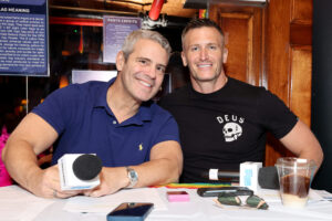 Andy Cohen (L) in blue polo shirt sitting next to John Hill, who is wearing a black tee shirt