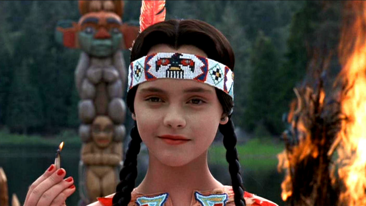 christina ricci as wednesday addams dresses in traditional native american headress while holding a match during thanksgiving speech