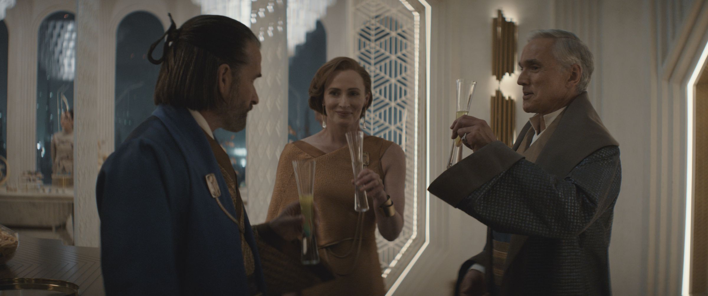 Two men and a woman in formal evening wear sharing a toast with one another at a soiree.