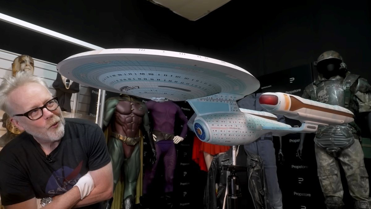 Adam Savage looks at a model of a Star Trek ship that is part of an auction