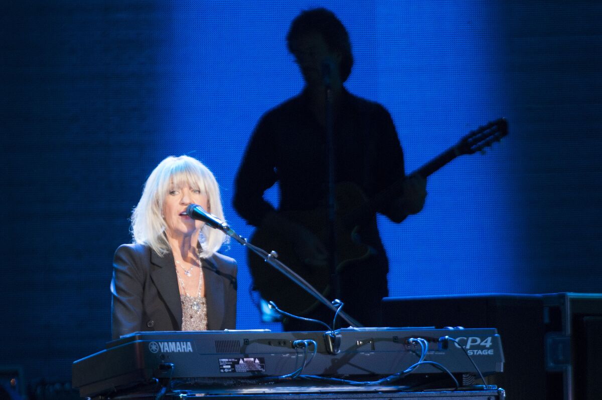 A woman sings and plays piano onstage.