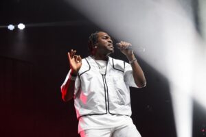 A rapper in all white performs onstage.