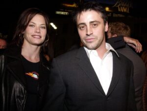 Matt LeBlanc (R) in black suit jacket standing next to Melissa McKnight, who is wearing a black outfit.