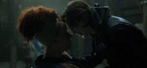 Kit and Jade embrace in a dark room in Willow.