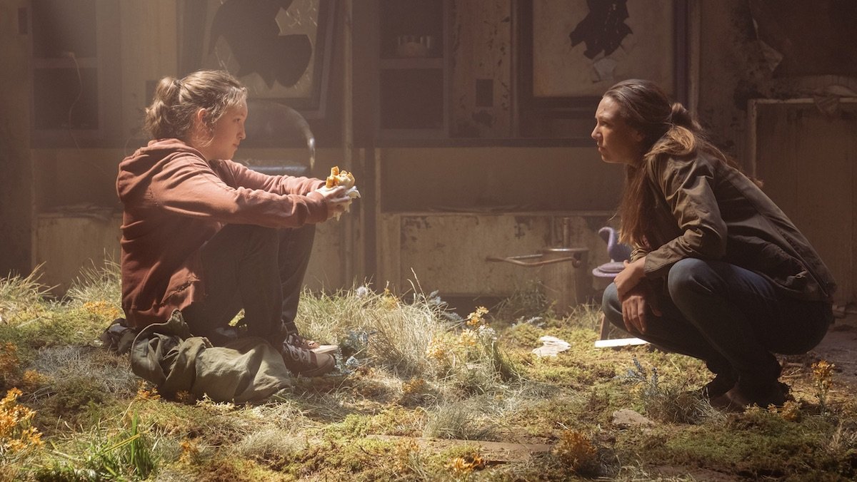 Bella Ramsey and Anna Torv sitting down talking in a barn in The Last Of Us trailer