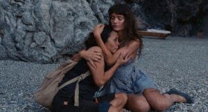 Two desperate women comfort each other on the beach in "Triangle of Sadness."