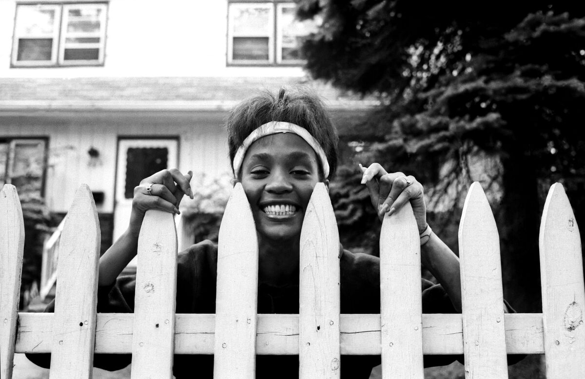 A young woman looks over a picket fence.