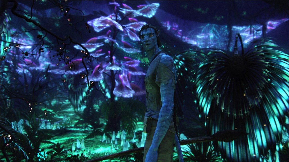 Jake's avatar stands among bioluminescent plants in Avatar