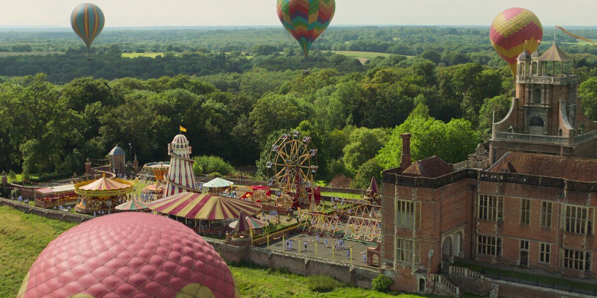 A large property with air balloons floating in the sky above.
