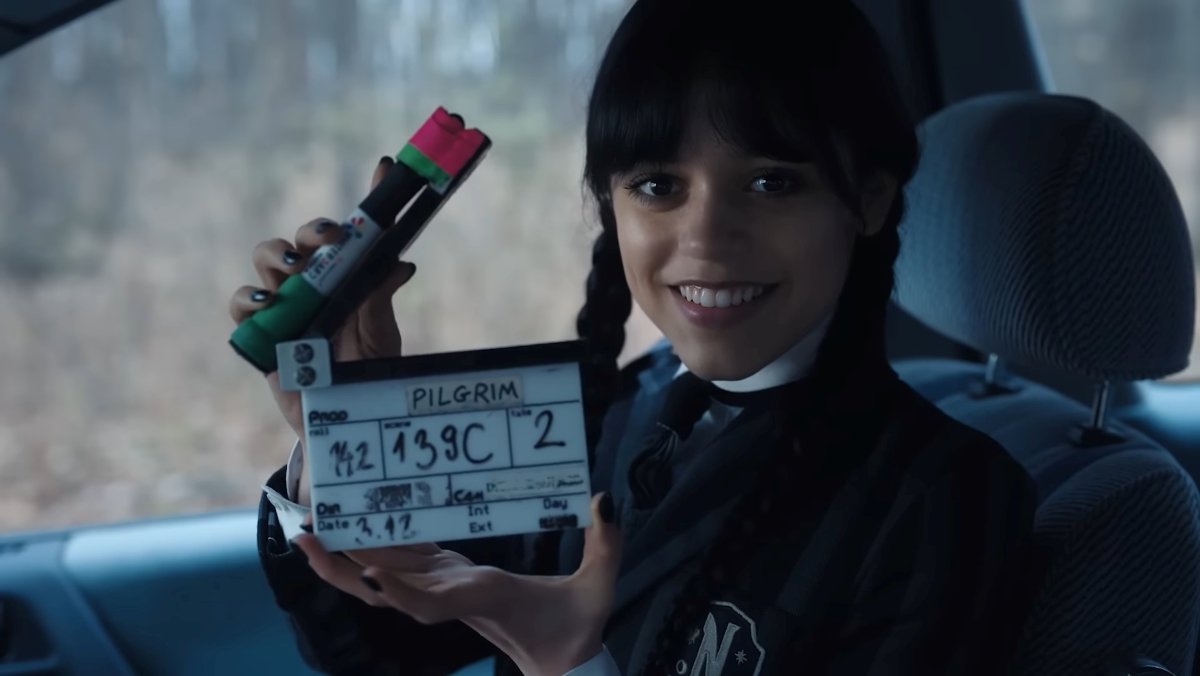 Jenna Ortega as Wednesday Addams smiles in a behind the scenes blooper