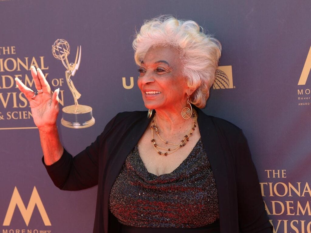 Nichelle Nichols smiling and doing the Vulcan "V" salute