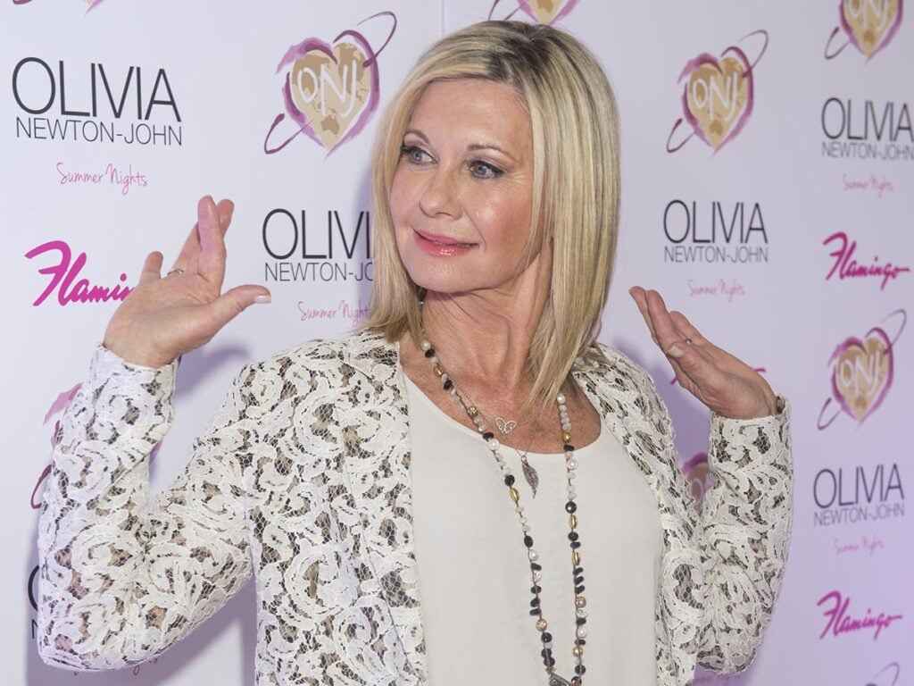Olivia Newton-John looking to the right and smiling. 