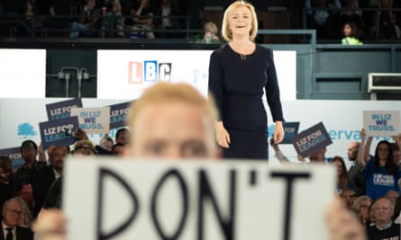 A protester holds up a placard as Liz Truss arrives on stage during a hustings event at Wembley Arena, London, as part of the campaign to be leader of the Conservative Party and the next prime minister.