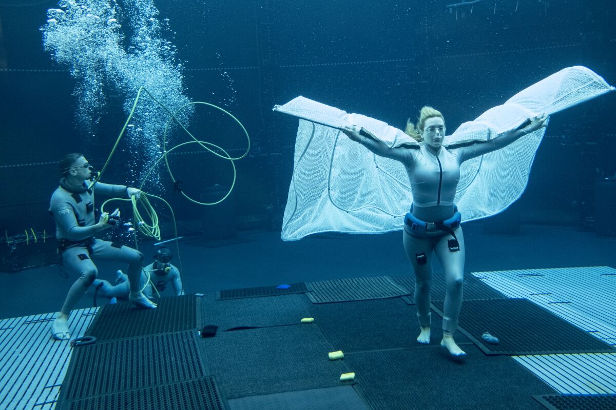 Film crew in wetsuits shoot Kate Winslet doing an underwater scene.