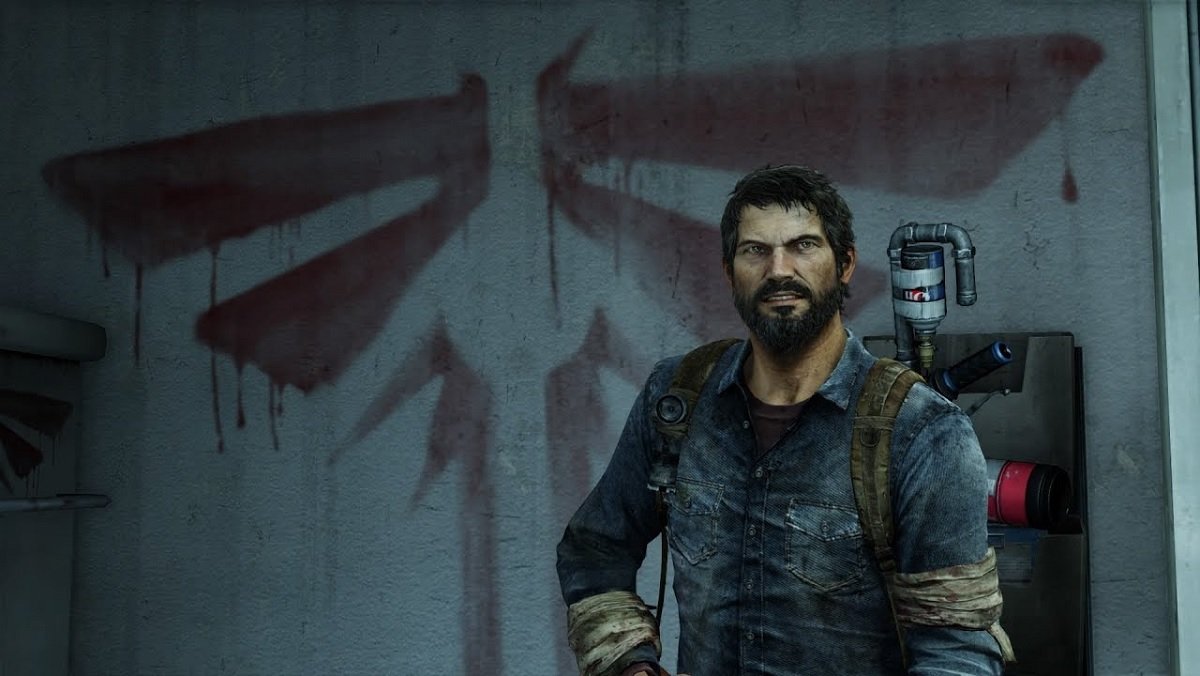 Joel stands in front of a wall emblazoned with the Fireflies logo in The Last of Us game.