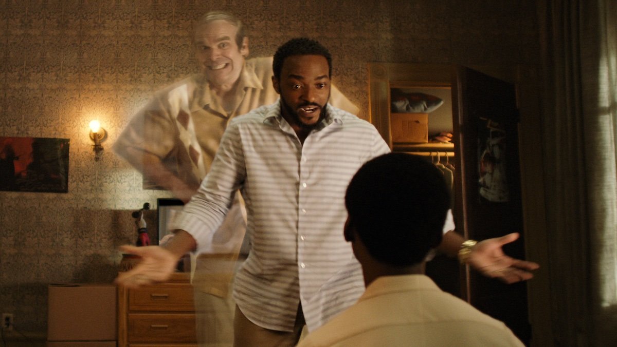 David Harbour as Ernest stands behind Anthony Mackie as Frank as he speaks to Jahi Winston as Kevin sitting on his bed in in We Have A Ghost. 