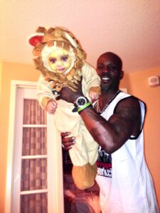 A father holding his daughter wearing a lion costume.