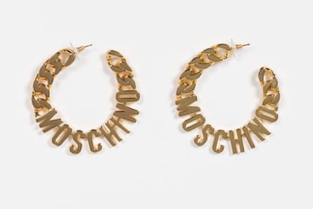 gold colored earrings say ‘moschino’ in a hoop shape