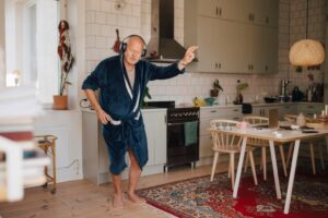 Man dancing in kitchen wearing headphones and bathrobe