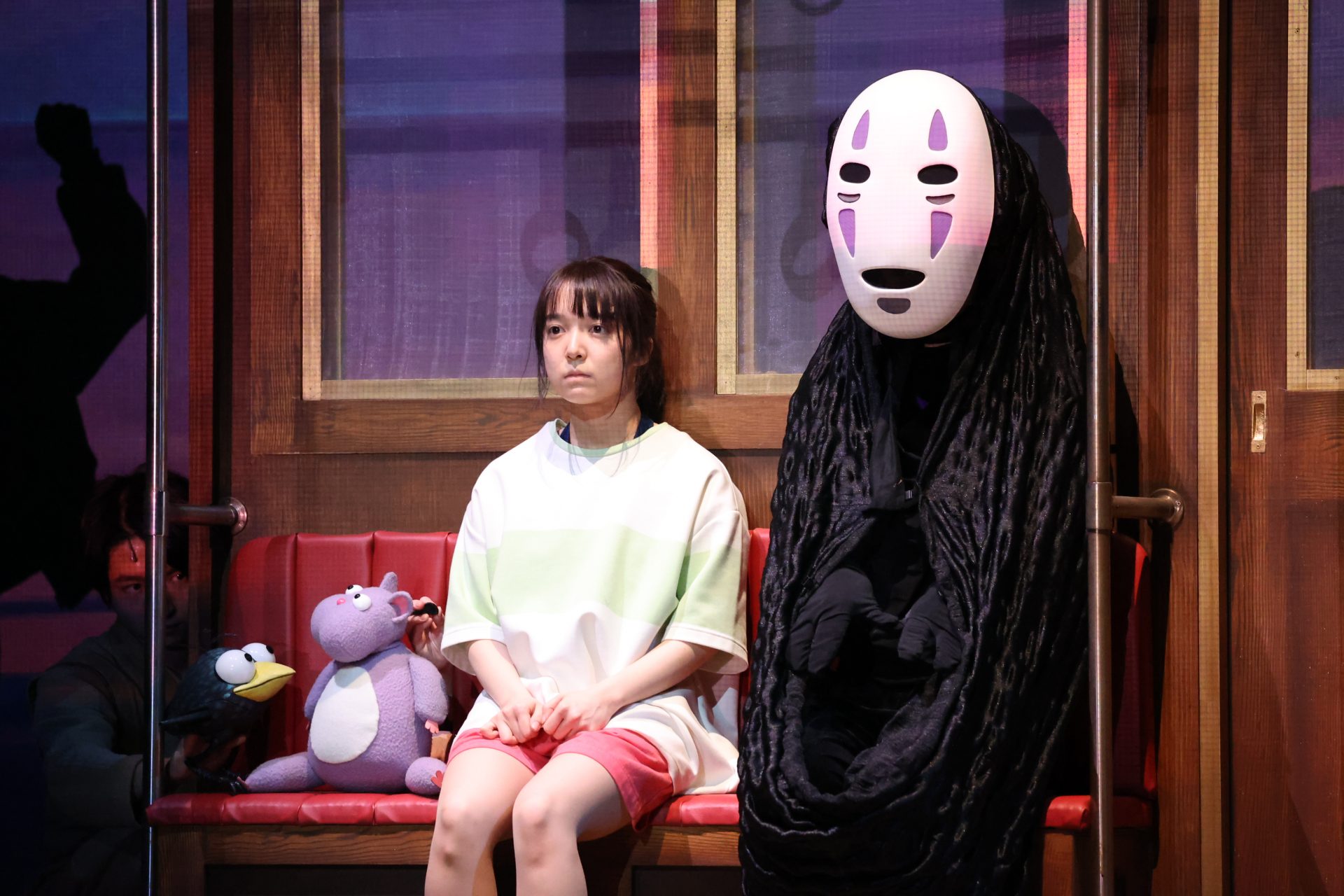 Chihiro sits beside No-Face in the stage adaptation of Spirited Away