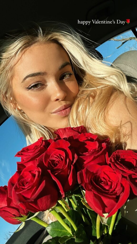 Olivia Dunne holding a bouquet of red roses.