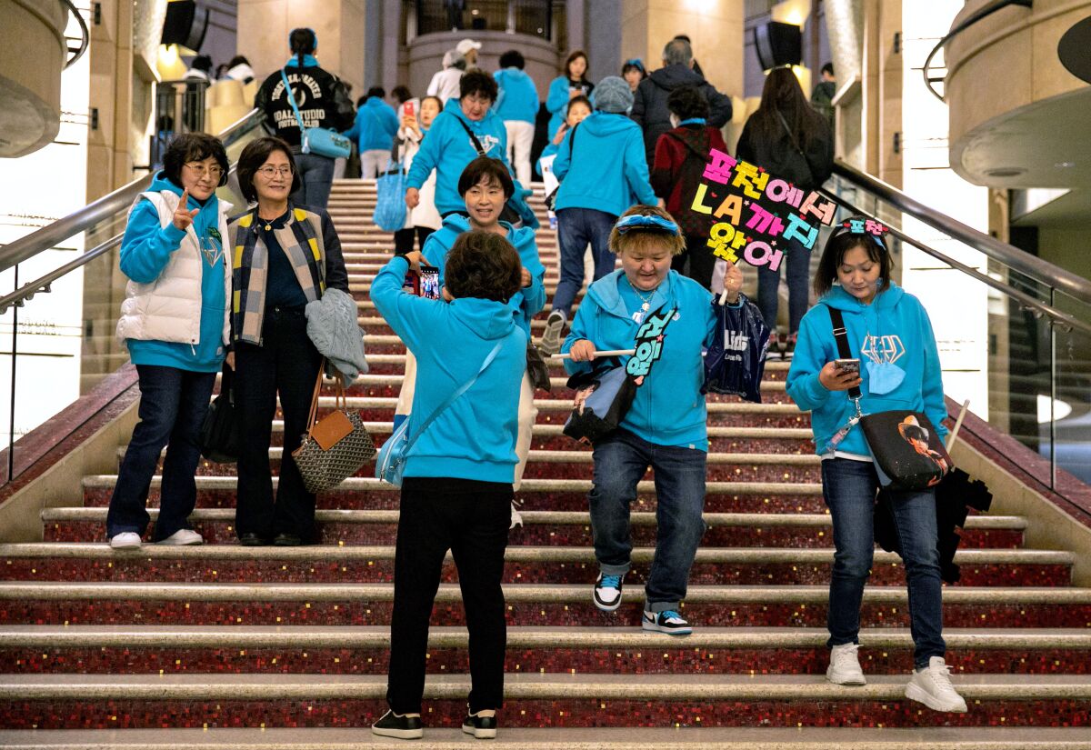 A group of people, dressed in teal sweatshirts, descent a wide staircase. 