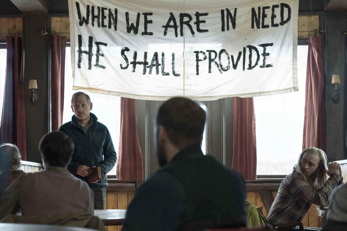 David (Scott Shepherd) standing in front of his people, with a banner behind him that reads “When we are in need he shall provide”