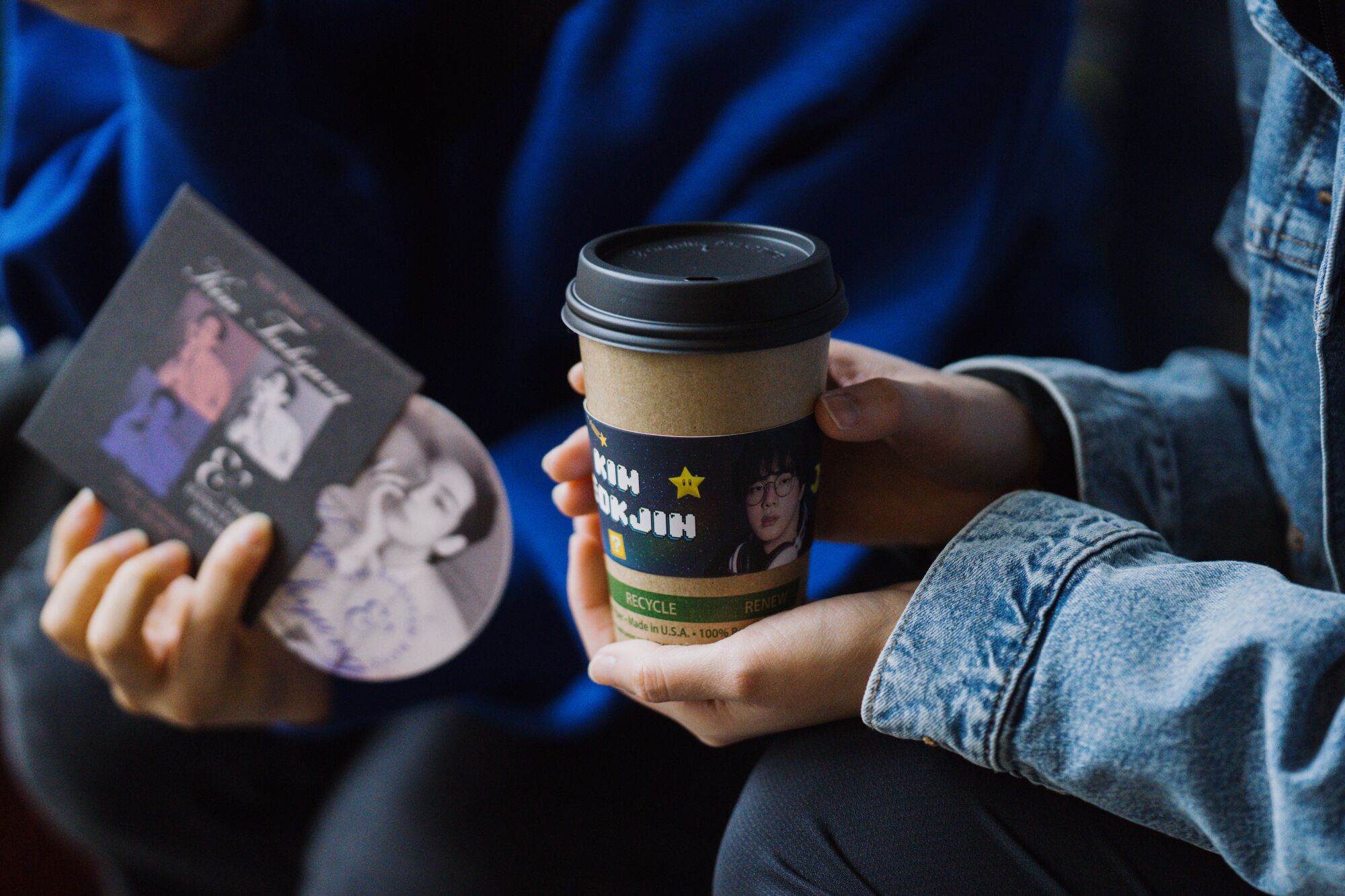 Fans hold merch and their freshly sleeved cups of tea during a cupsleeve event at R&B Tea.