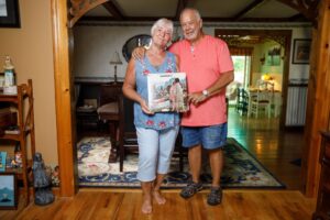 Bobbi Ercoline, left, and Nick Ercoline, right, hold a copy of the Woodstock album with the iconic photo in their house.