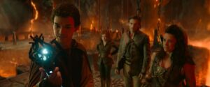 LtR: Justice Smith plays Simon, Sophia Lillis plays Doric, Michelle Rodriguez plays Holga and Chris Pine plays Edgin in Dungeons &amp; Dragons: Honor Among Thieves. Simon holds up a glowing wand as the others look on, in a rocky, lava-filled cave.