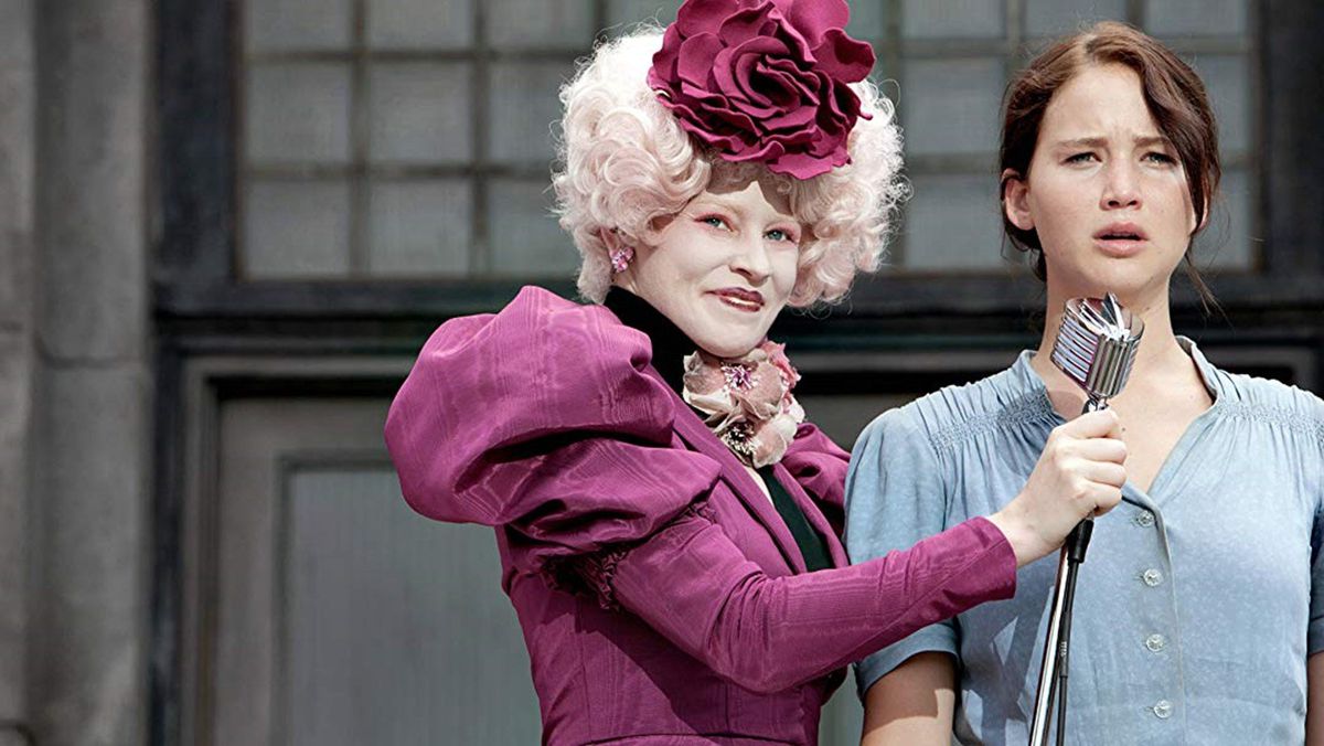 Effie (Elizabeth Banks) holds a microphone out to Katniss (Jennifer Lawrence)