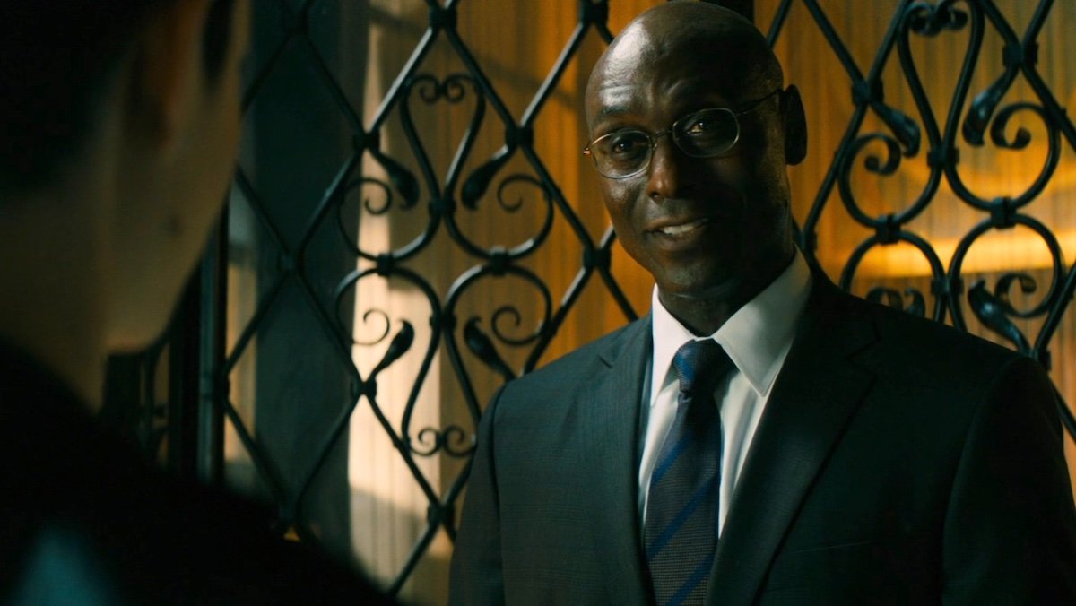 Lance Reddick as the Continental's concierge Charon smiles at the Adjudicator in John Wick: Chapter 3